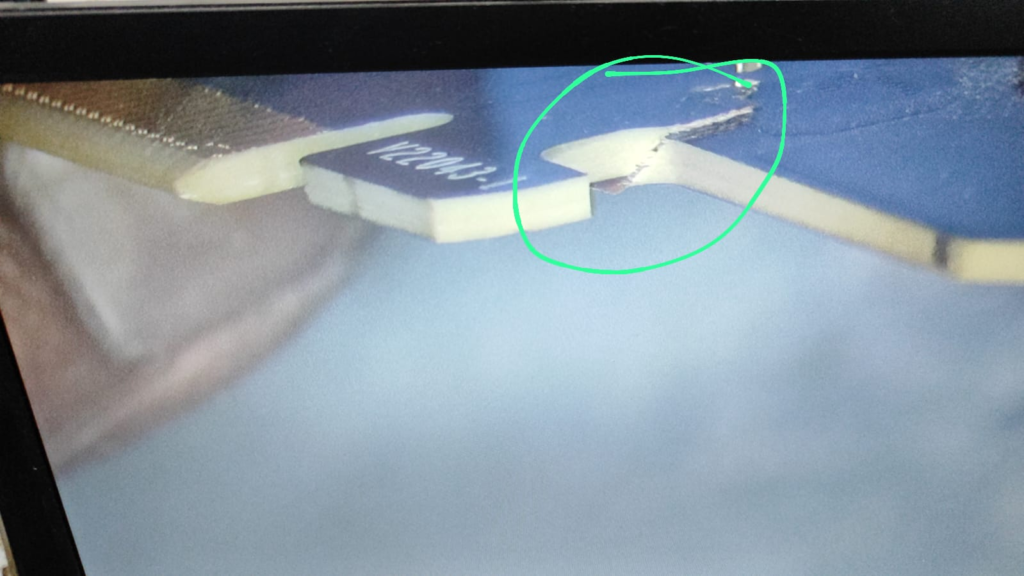 Close-up view of a damaged GPU PCB near the PCIe connector, showing a noticeable crack highlighted in green.