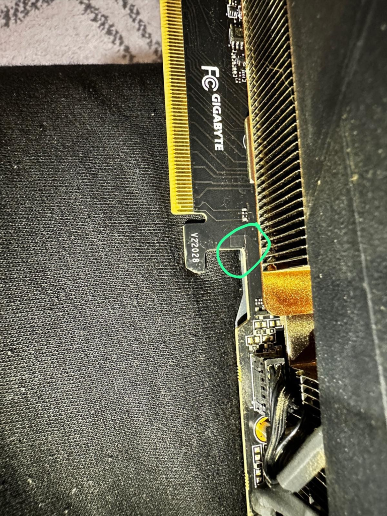 Close-up of a graphics card PCB showing a highlighted crack near the PCIe connector, indicating potential damage.